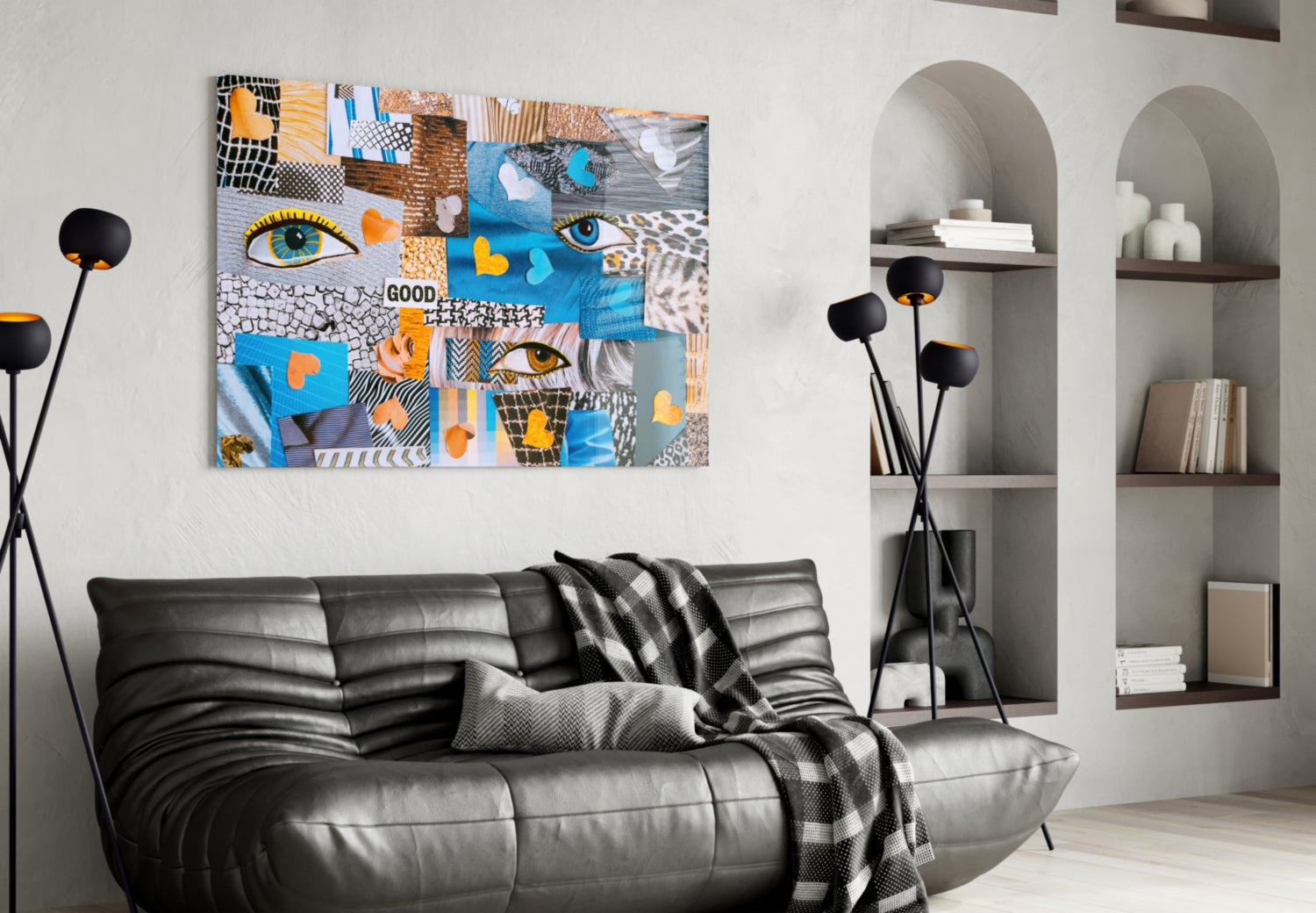 Colorful abstract glass wall art with blue, orange, and yellow patchwork patterns featuring eyes and "GOOD" text, displayed above a black leather sofa in a modern living room.