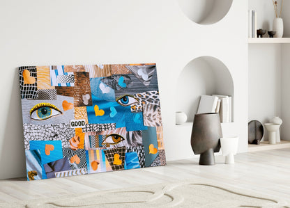 Colorful glass wall art leaning against white wall displaying patchwork of eyes, hearts, patterns in blue, orange, and black.