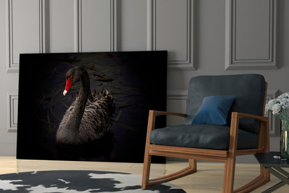 Black swan glass wall art displayed in modern living room beside wooden chair with dark cushions and potted flowers.
