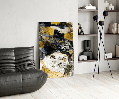 Modern living room interior with abstract gold and black glass wall art displayed beside a gray leather chair and floor lamp with spherical accents.
