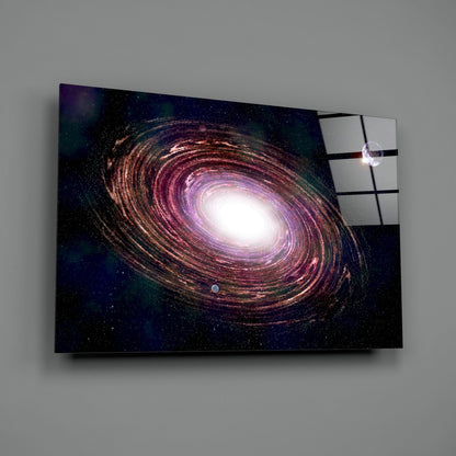 Glass wall art displaying a spiral galaxy with purple, gold, and white tones against a starry dark background, shown at an angle with shadow.