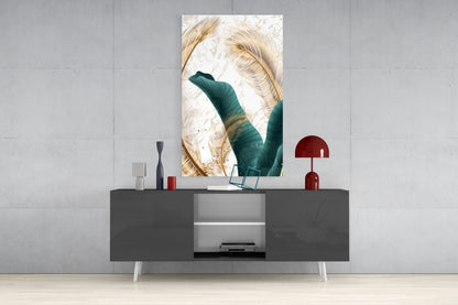 Vertical glass wall art featuring golden feathers and teal green leaves displayed above a dark console table with red decorative lamp.