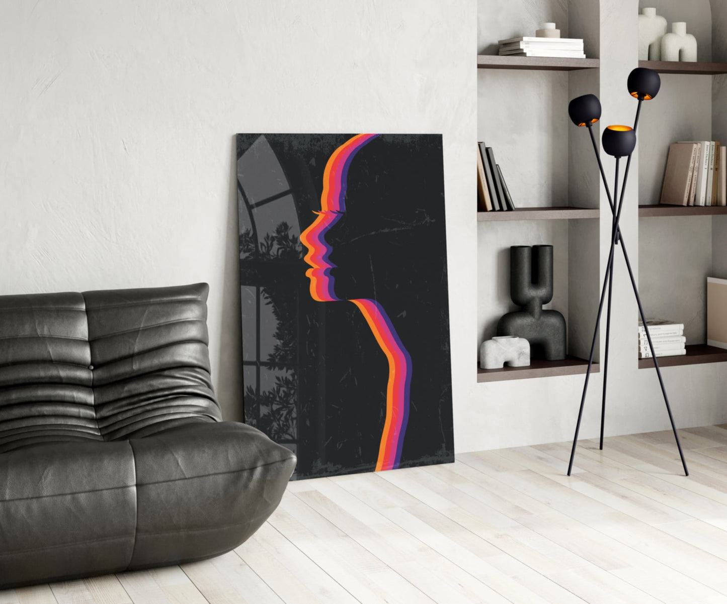 Modern living room with dark leather sofa, abstract colorful striped face artwork on black canvas, and tripod floor lamp with black spheres.
