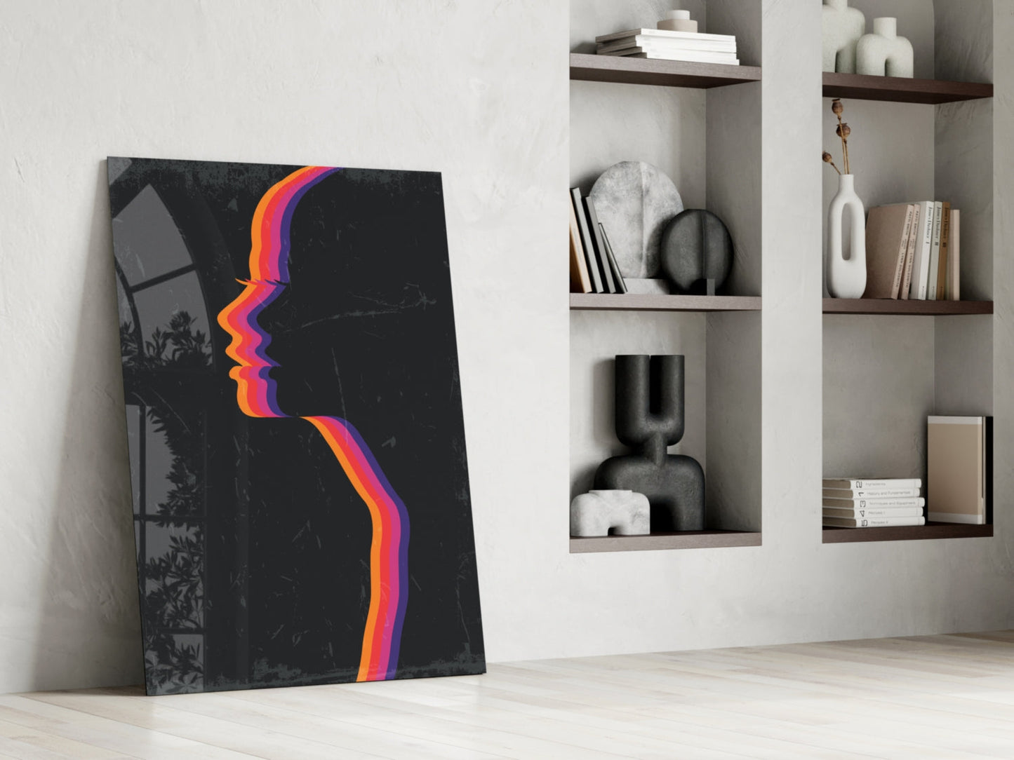 Modern interior scene showing black glass wall art with colorful rainbow gradient profile design leaning against white wall beside built-in shelving.