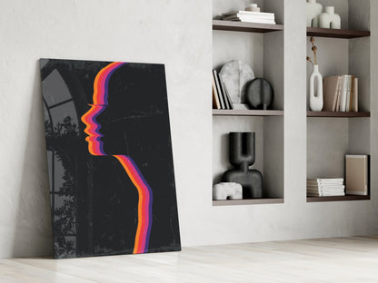 Modern interior scene showing black glass wall art with colorful rainbow gradient profile design leaning against white wall beside built-in shelving.