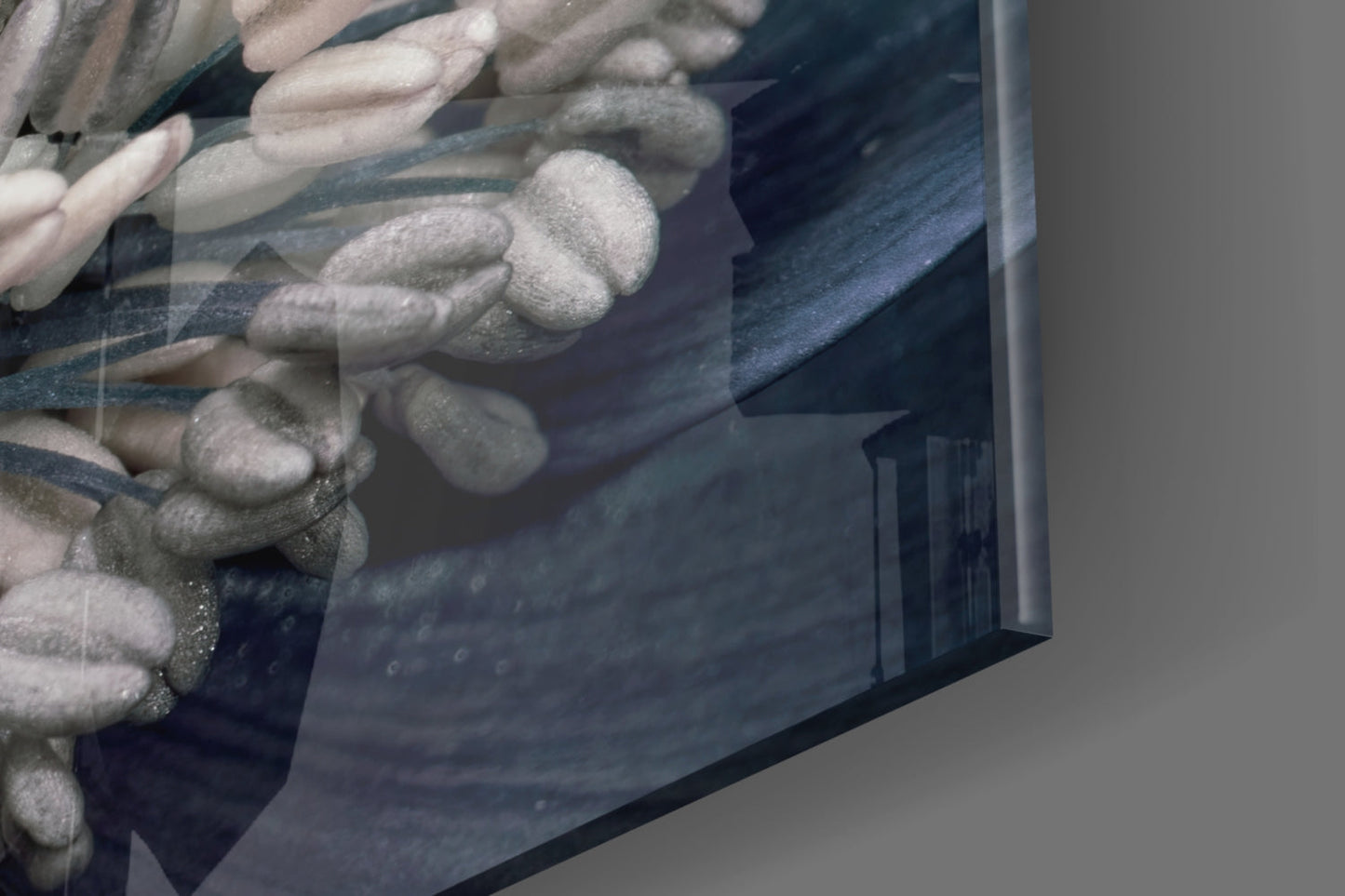 Close-up angled view of gray flower glass wall art showing textured floral relief details and dark blue-gray tones on glass surface.
