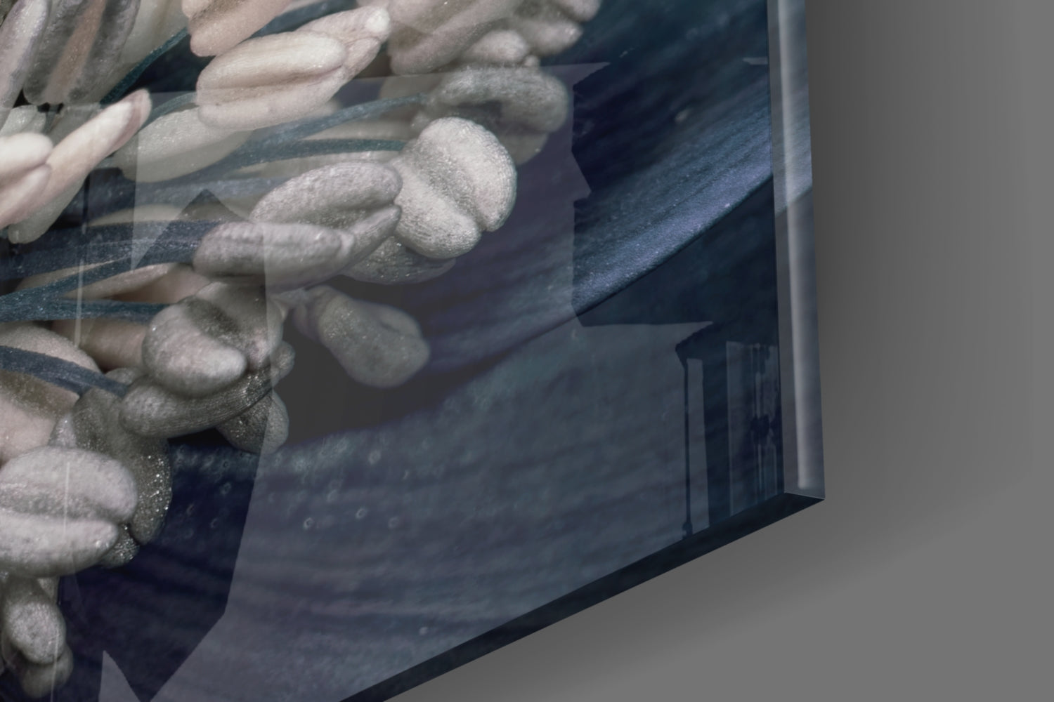 Close-up angled view of gray flower glass wall art showing textured floral relief details and dark blue-gray tones on glass surface.