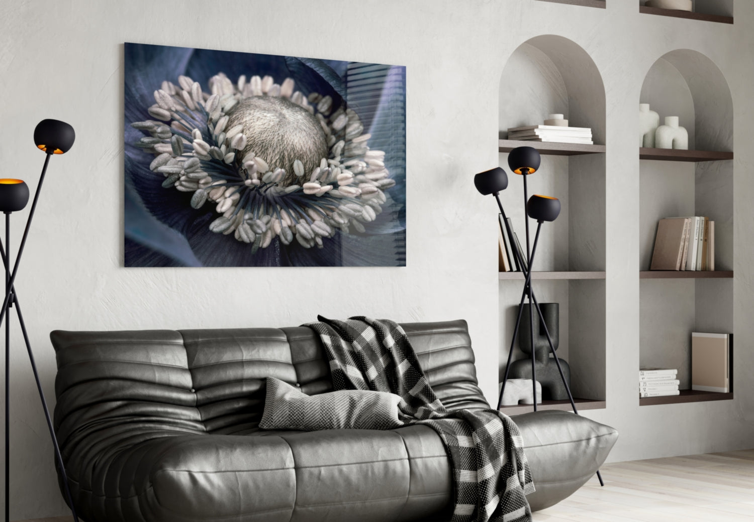 Gray flower glass wall art displayed above black leather sofa in modern living room with white shelving.