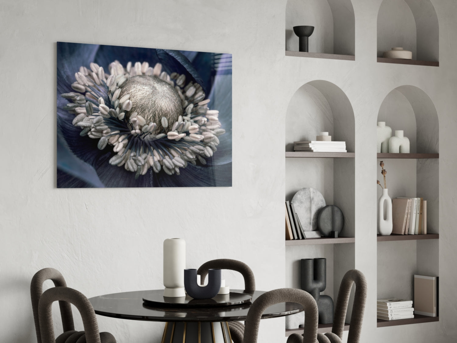 Gray flower glass wall art displaying a white daisy with dark blue background, hung above a black dining table in a modern interior.