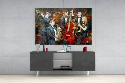 Colorful glass wall art depicting jazz musicians with instruments displayed above a dark gray media console in a minimalist interior setting.