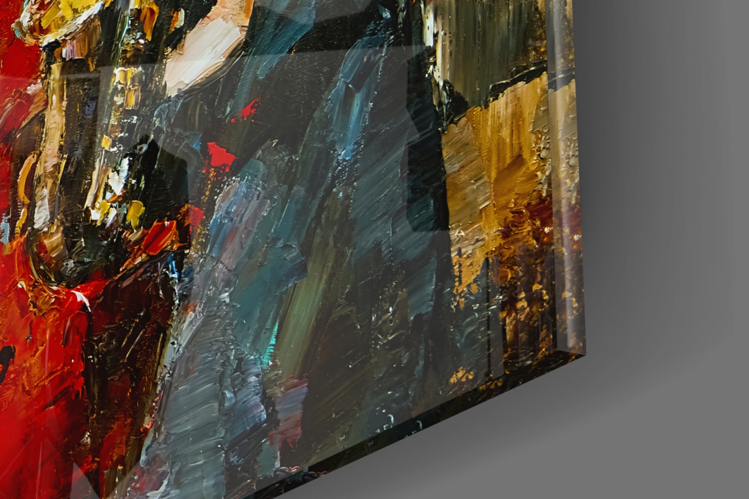 Close-up angled view of textured glass wall art with bold red, yellow, gold, teal, and black brushstroke patterns against gray background.