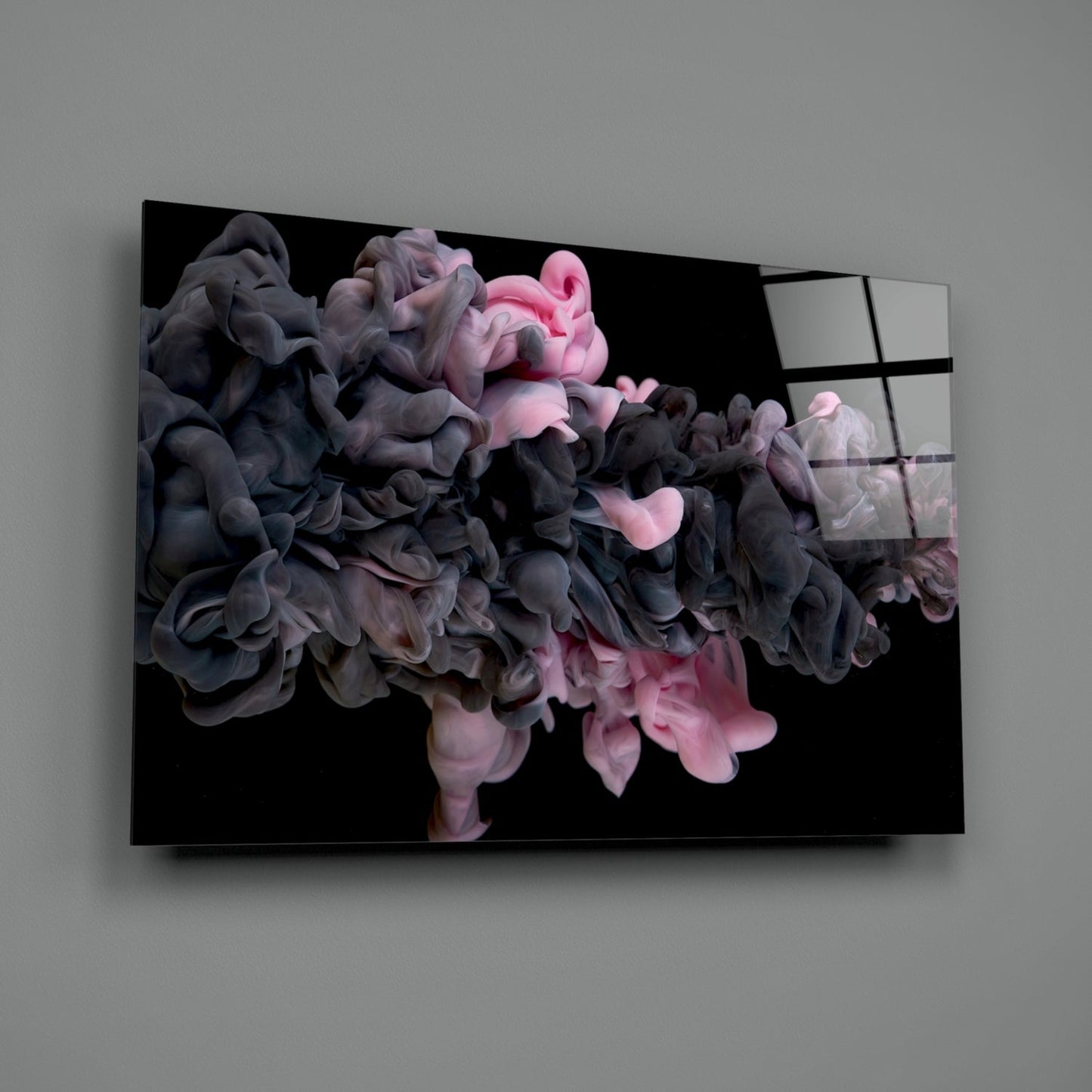 Glass wall art panel displaying swirling pink and dark gray smoke clouds against black background, mounted at angle on gray wall.