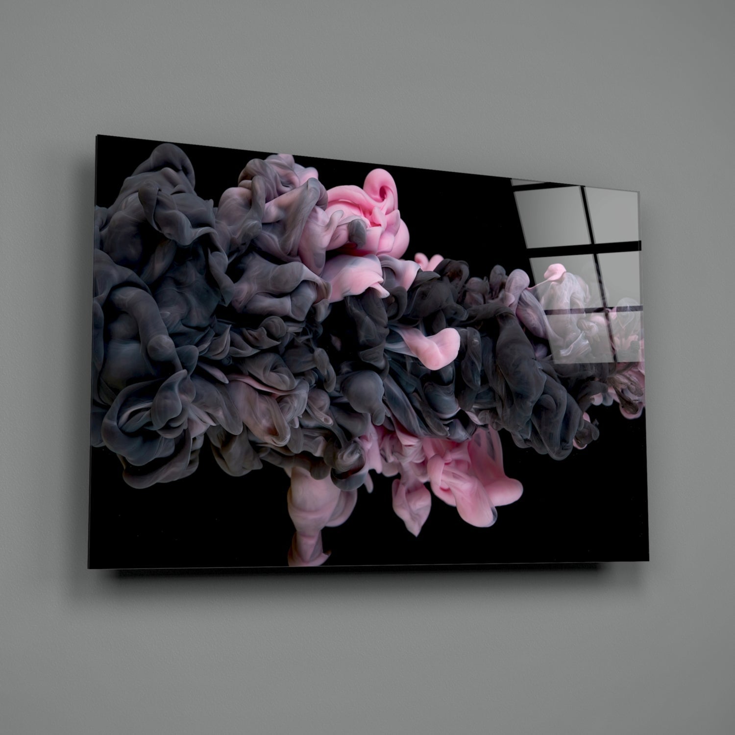 Glass wall art panel displaying swirling pink and dark gray smoke clouds against black background, mounted at angle on gray wall.