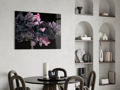 Pink and black swirling smoke design on glass art displayed above black dining table in modern interior with white built-in shelving.