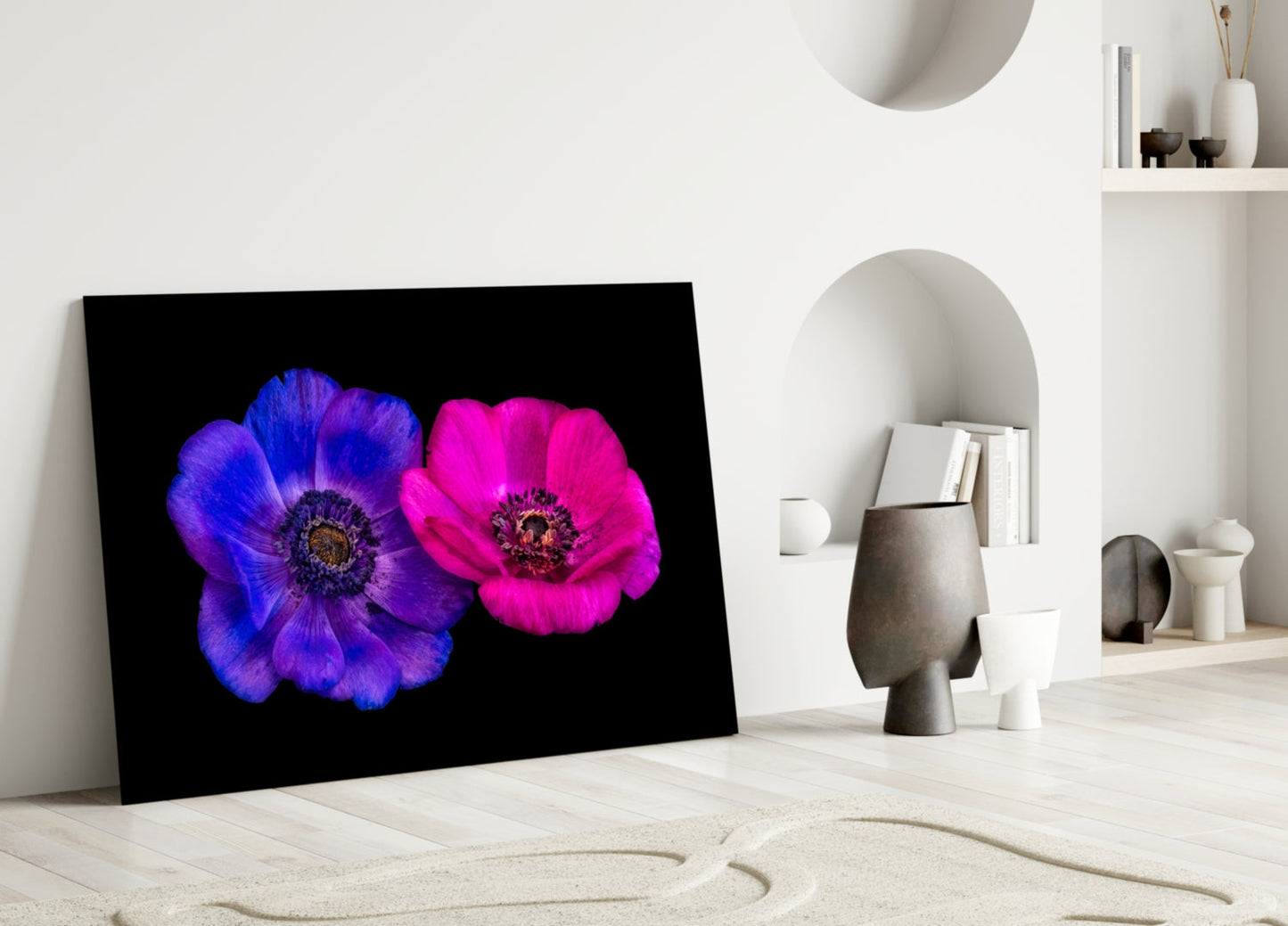 Glass wall art featuring vibrant blue and magenta flowers on black background, displayed leaning against white interior wall.