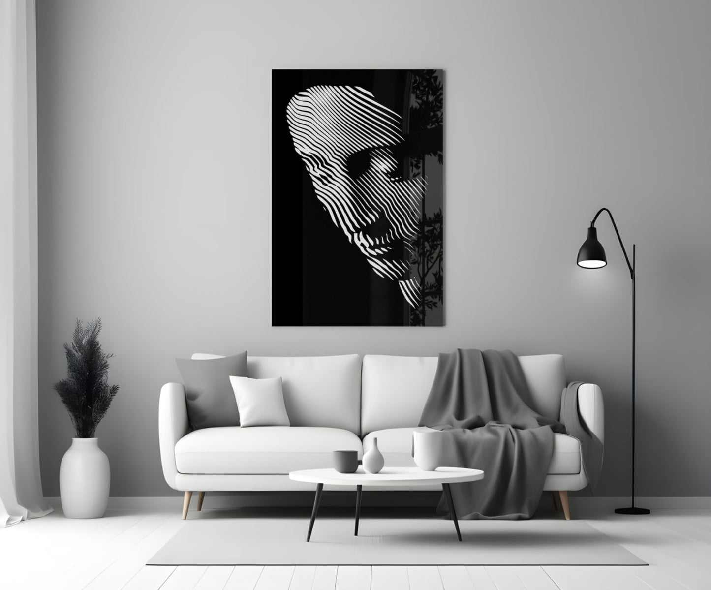 Black and white glass wall art featuring abstract striped face portrait displayed above white sofa in minimalist living room setting.