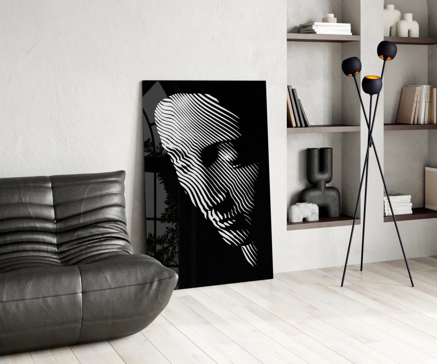 Black and white striped portrait glass art leaning against white wall in modern living room with gray sofa and shelving.