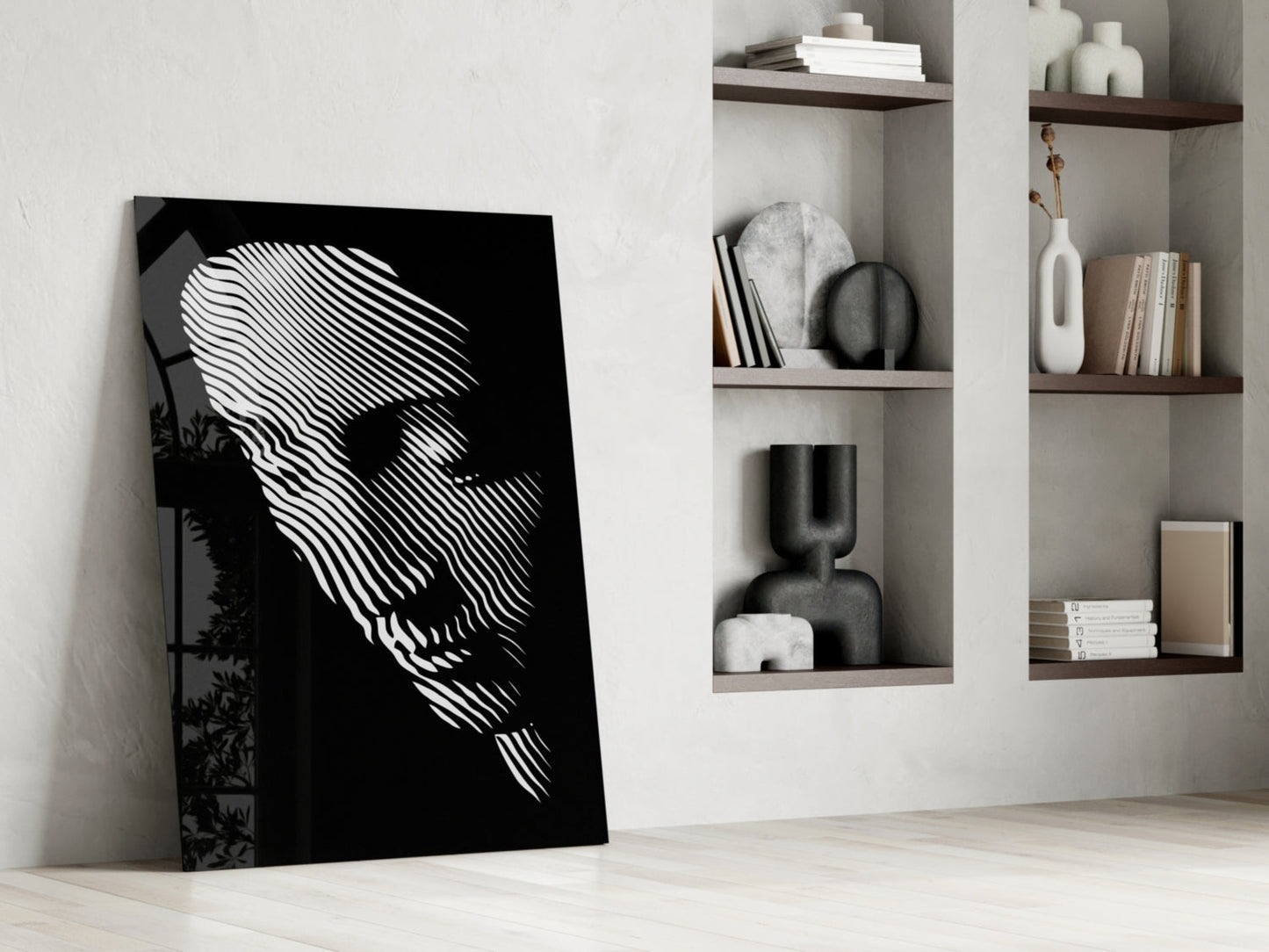 Black and white striped face portrait leaning against white wall beside built-in shelving with decorative objects and books.
