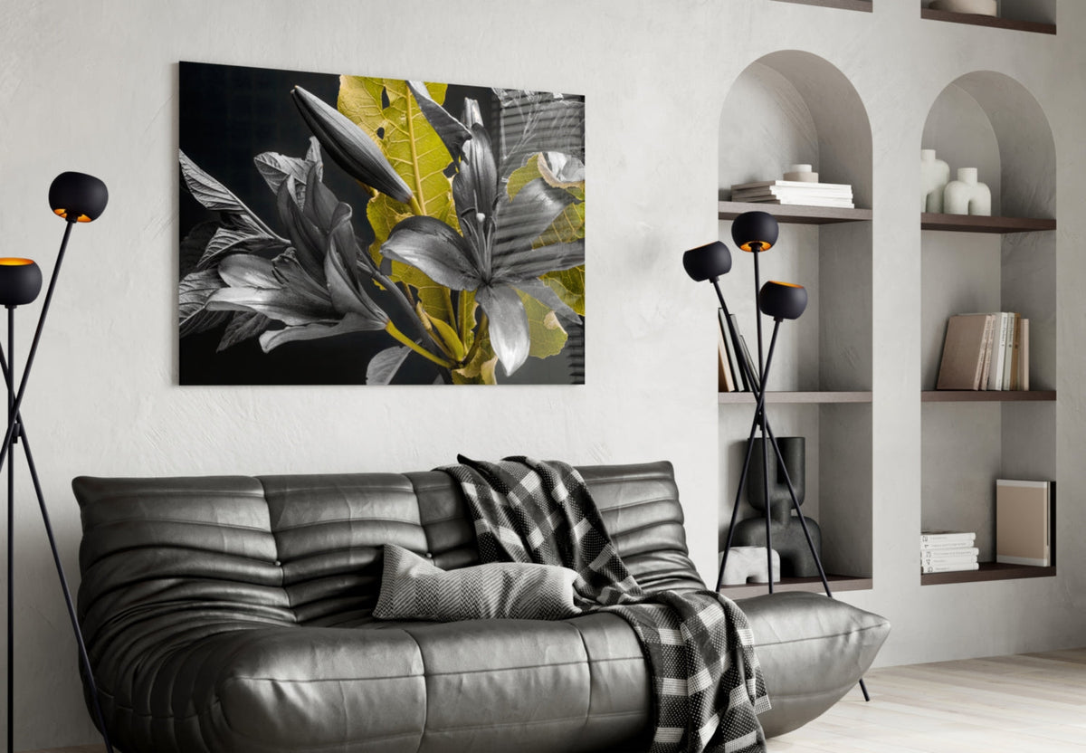 Black and gold lily artwork displayed above gray leather sofa in modern living room with built-in shelving.