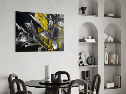 Gold Leaf Lilies on Black Glass wall art displayed above a round black dining table with upholstered chairs in a modern interior setting.