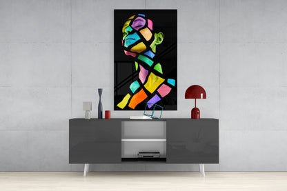 Colorful Spirit Glass Wall Art displayed above a gray media console, showing vibrant multicolored geometric portrait on black background.