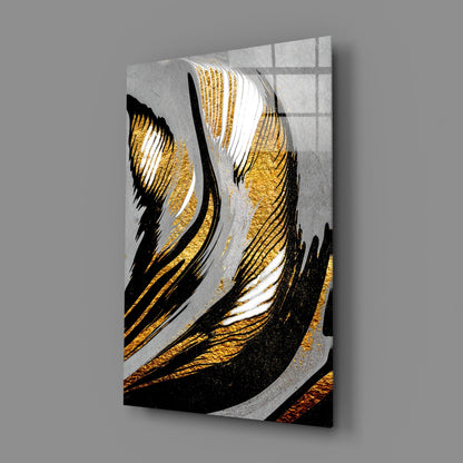 Angled perspective view of glass wall art featuring black and gold brushstrokes with white accents on gray background, mounted on wall.