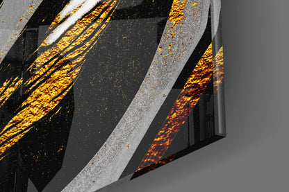 Close-up angled view of Golden Wings glass wall art showing layered gray and black panels with gold and orange textured surfaces.