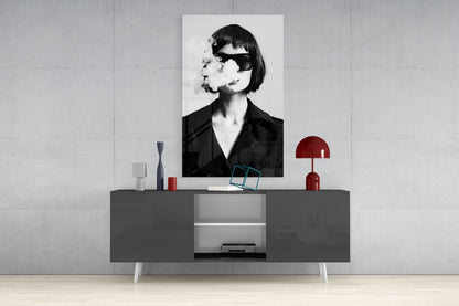 Black and white portrait of woman wearing sunglasses and black shirt, displayed on wall above gray console table with red lamp and decorative objects.
