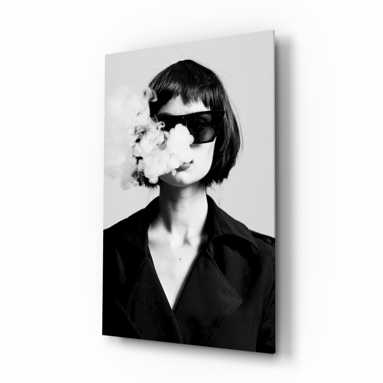 Black and white portrait of woman wearing dark blazer and oversized sunglasses, exhaling smoke, mounted on glass wall art panel.