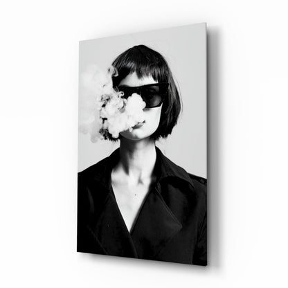 Black and white portrait of woman wearing dark blazer and oversized sunglasses, exhaling smoke, mounted on glass wall art panel.