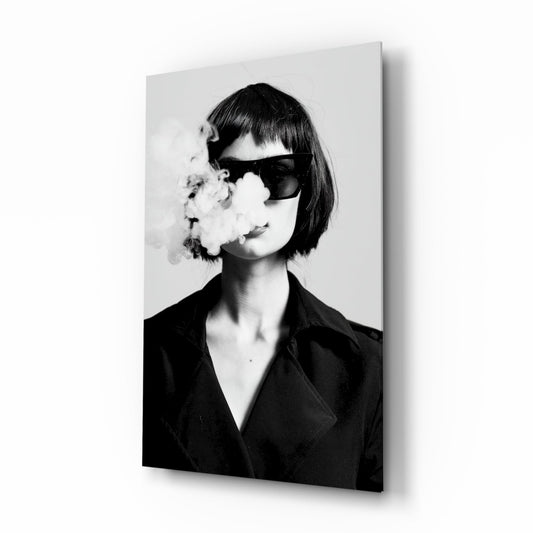 Black and white portrait of woman wearing dark blazer and oversized sunglasses, exhaling smoke, mounted on glass wall art panel.
