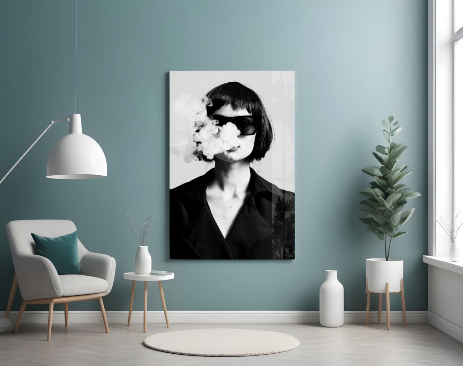 Black and white portrait canvas depicting woman wearing sunglasses with smoke, displayed on teal wall beside chair and plants.