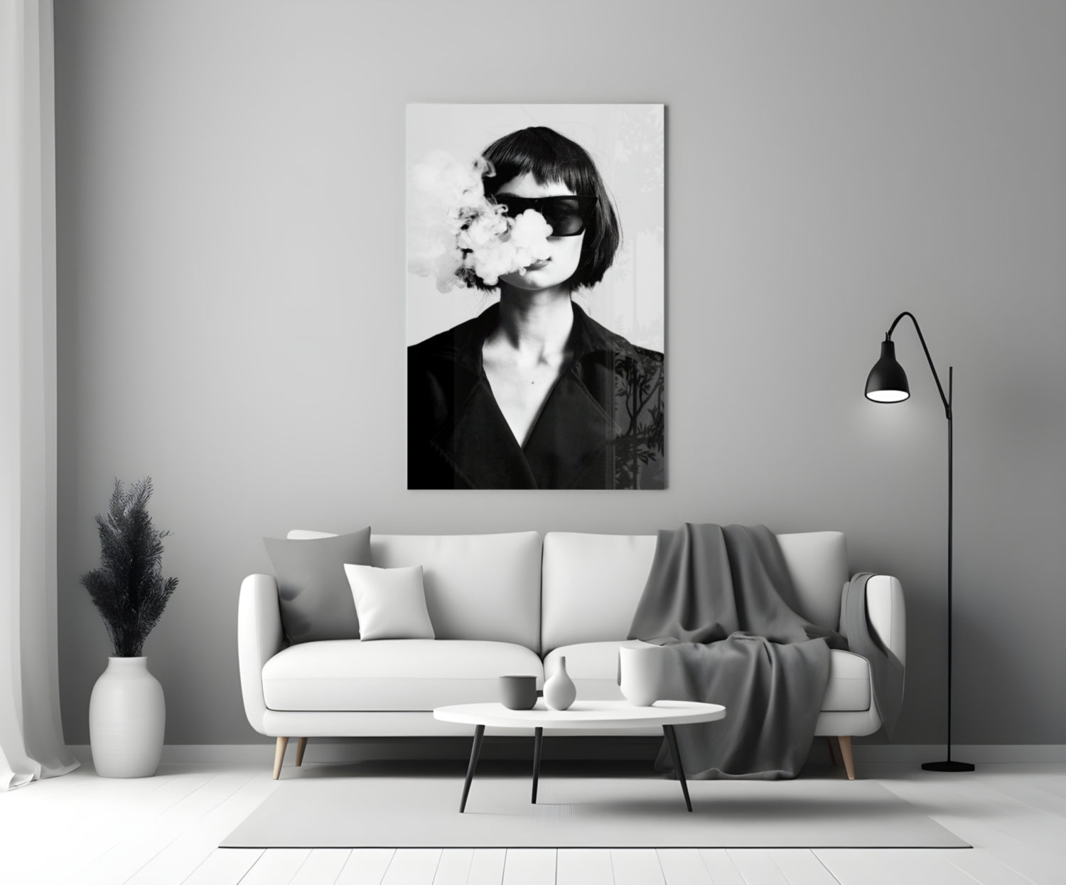 Black and white portrait of woman wearing sunglasses exhaling smoke, displayed as framed wall art above living room sofa.