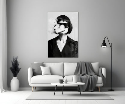 Black and white portrait of woman wearing sunglasses exhaling smoke, displayed as framed wall art above living room sofa.