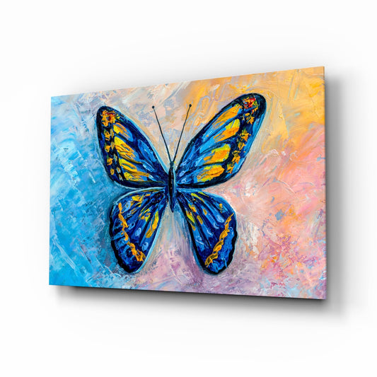 A blue and gold butterfly with black outlines displayed on angled glass art against a gradient background transitioning from blue to pink and yellow.