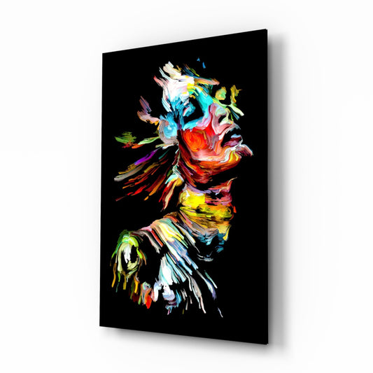 Angled three-quarter view of black glass wall art displaying a colorful abstract portrait with vibrant brushstrokes in red, yellow, blue, and green against a black background.