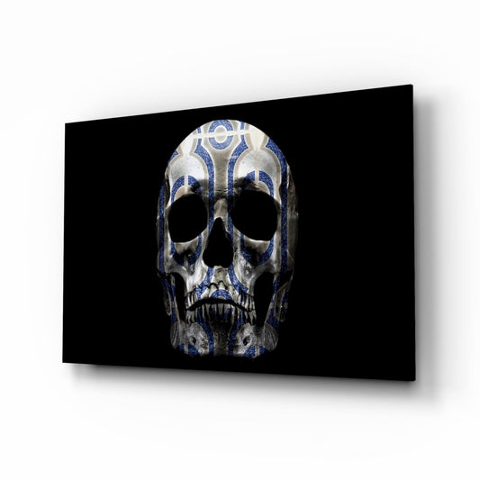 Angled perspective view of a glass skull with blue and white tribal patterns mounted on a black background panel.