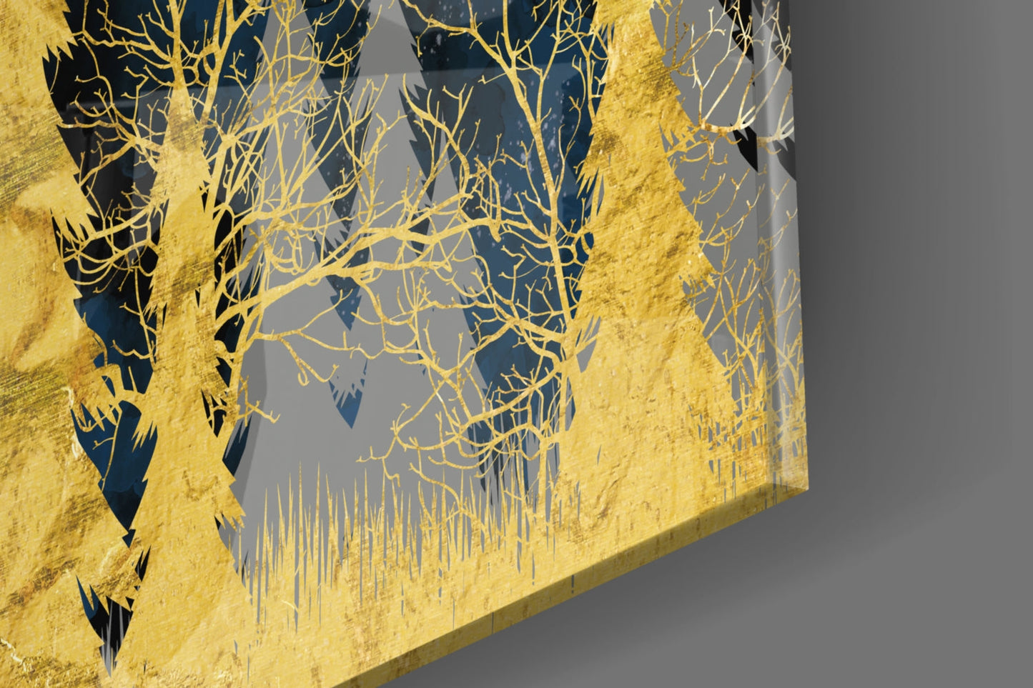 Close-up angled view of gold-foiled bare tree branches and grass silhouettes on dark blue and gray glass panel.