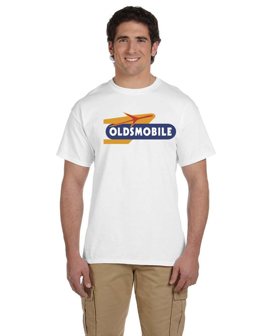 Front view of a smiling man in a white crew-neck tee printed with a red, gold and navy Oldsmobile logo.