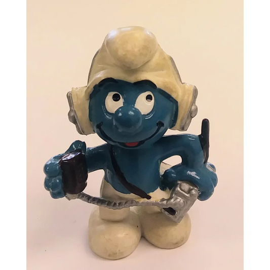 Operator Smurf figurine in white hat, blue body, holding microphone