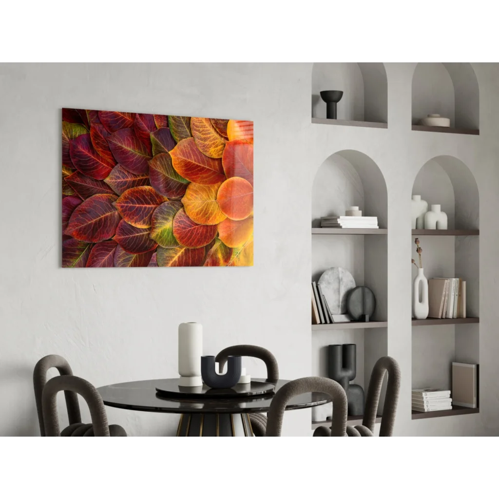 Vibrant autumn leaves glass wall art in reds, oranges, golds on white wall