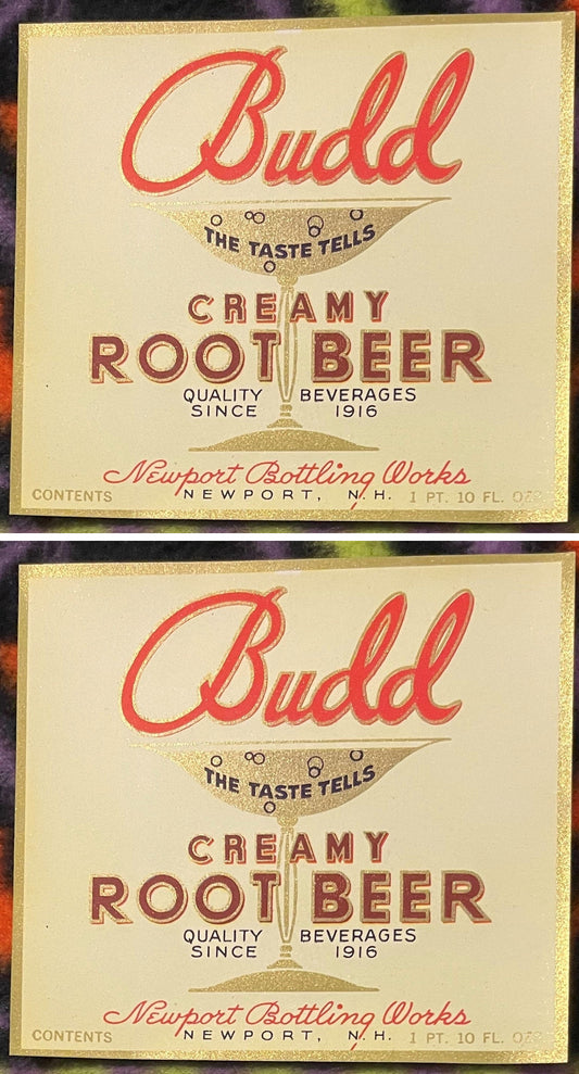 Two Budd Creamy Root Beer labels, one above the other: red Budd script over a gold soda glass reading THE TASTE TELLS, CREAMY ROOT BEER in maroon, Quality Beverages Since 1916, Newport Bottling Works, Newport, N.H.