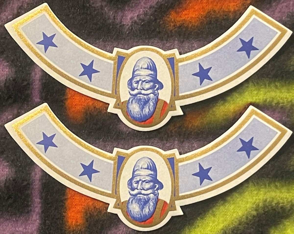 Two antique Viking neck labels, one above the other on a colorful fleece: a bearded Norseman in a tall blue cap in a gold-framed oval, blue stars on curved grey-blue arms, gold rules.