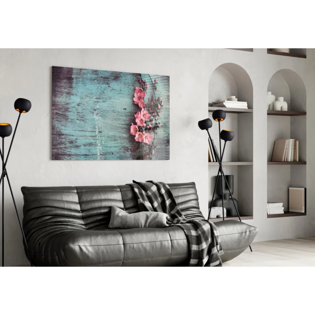 Gray leather sofa with plaid blanket under pink blossoms wall art