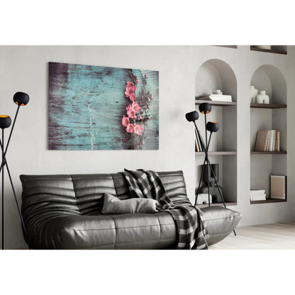 Gray leather sofa with plaid blanket under pink blossoms wall art