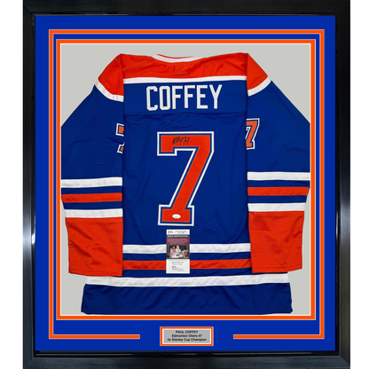 Framed Edmonton Oilers blue hockey jersey number 7 signed by Paul Coffey, displayed front-facing with red and white stripes and JSA authentication certificate visible.