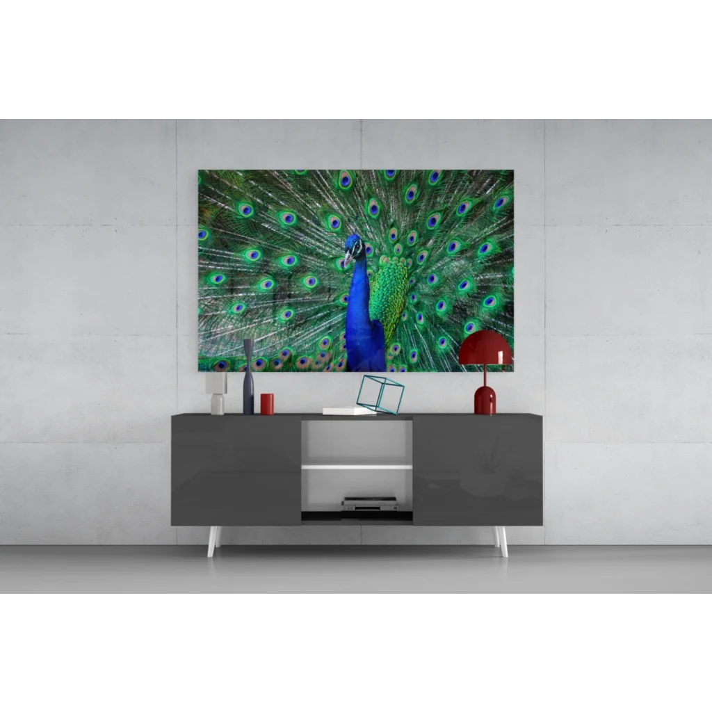 Vibrant peacock glass wall art with iridescent blue green feathers on gray table