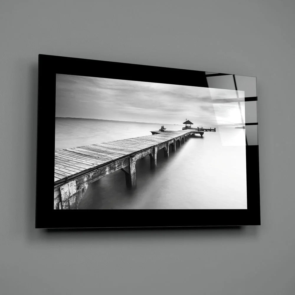 Black-and-white glass wall art of wooden pier in calm water