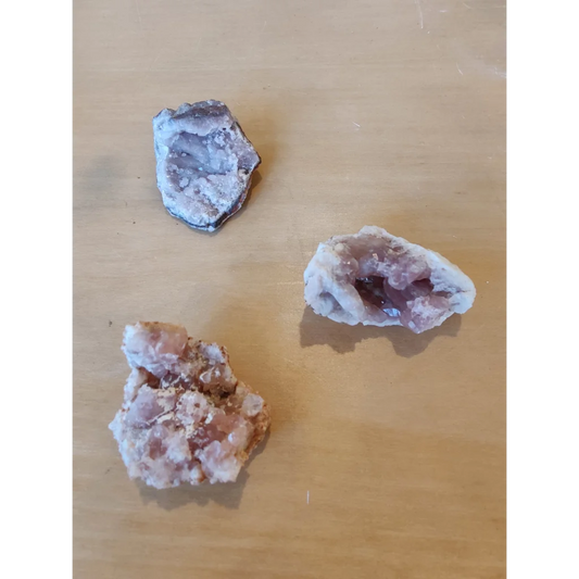 Three pink amethyst geodes with purple white crystalline interiors