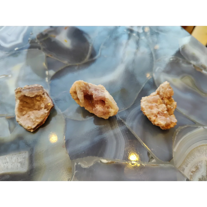 Three light brown geodes on pink amethyst agate slab